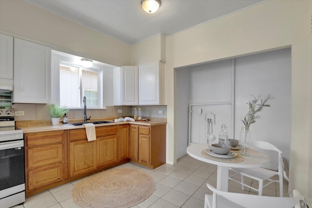 kitchen featuring a sink, white electric range oven, light tile patterned floors, and light countertops