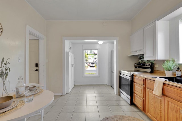 kitchen featuring refrigerator, light countertops, stainless steel electric range, under cabinet range hood, and light tile patterned floors