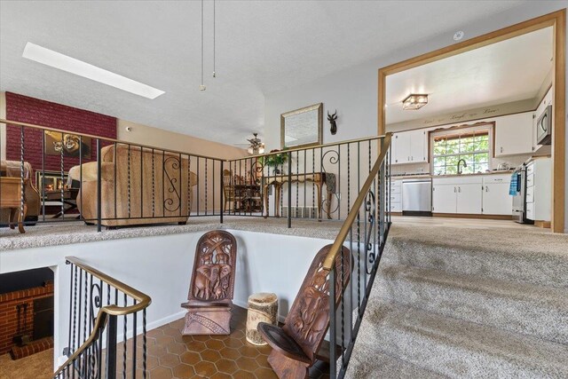 staircase featuring a ceiling fan and a skylight