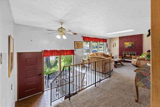 living area featuring a textured ceiling, ceiling fan, and a fireplace