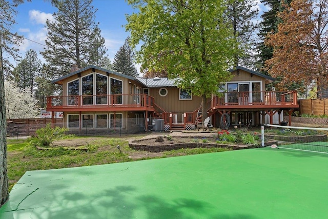 back of house with metal roof, a wooden deck, central air condition unit, fence, and stairs