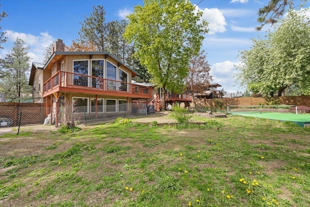 rear view of house with a wooden deck, a fenced backyard, and a chimney