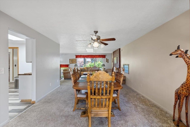 carpeted dining room with baseboards, a ceiling fan, and a textured ceiling