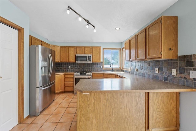kitchen featuring a peninsula, light tile patterned floors, a sink, appliances with stainless steel finishes, and backsplash