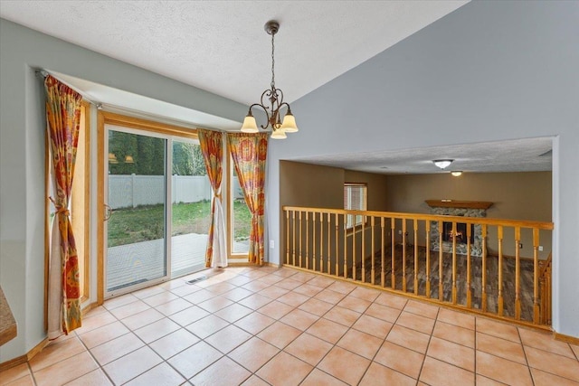 unfurnished room with an inviting chandelier, tile patterned flooring, a textured ceiling, and lofted ceiling