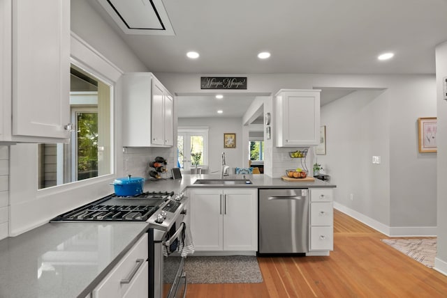 kitchen with a sink, appliances with stainless steel finishes, white cabinets, and tasteful backsplash