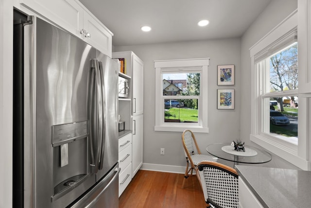 kitchen with baseboards, appliances with stainless steel finishes, a wealth of natural light, and wood finished floors