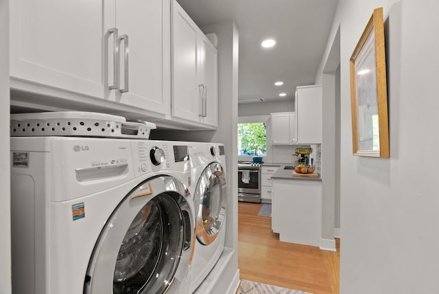 clothes washing area featuring light wood finished floors, washing machine and dryer, recessed lighting, and cabinet space