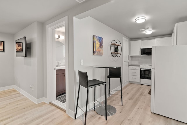 kitchen featuring decorative backsplash, white appliances, baseboards, white cabinets, and light wood-style flooring