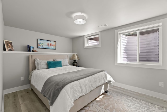 bedroom featuring baseboards, wood finished floors, and visible vents