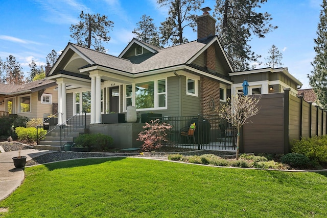 view of front of home featuring fence, a chimney, a shingled roof, and a front yard