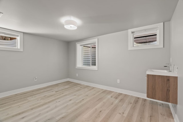 interior space with a sink, baseboards, and light wood-style floors