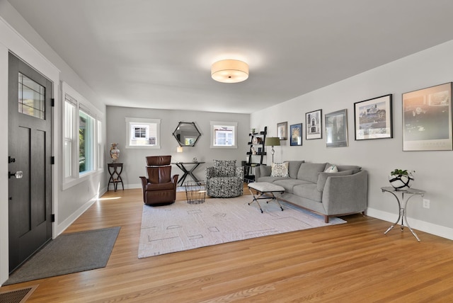 living area featuring baseboards, visible vents, and wood finished floors