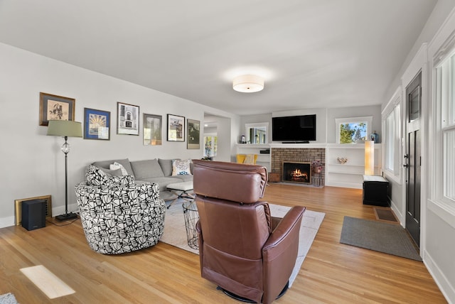 living area featuring baseboards, light wood-style flooring, and a fireplace