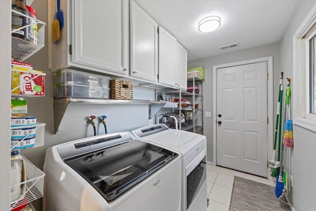 laundry room with washer and dryer, light tile patterned flooring, cabinet space, a textured ceiling, and visible vents