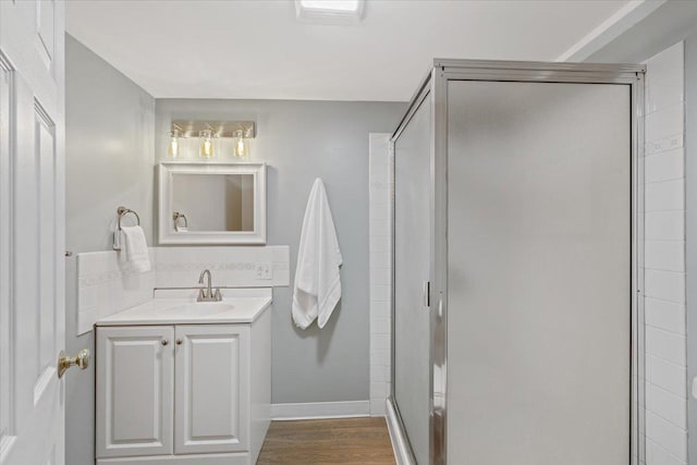 bathroom featuring backsplash, a shower stall, wood finished floors, vanity, and baseboards