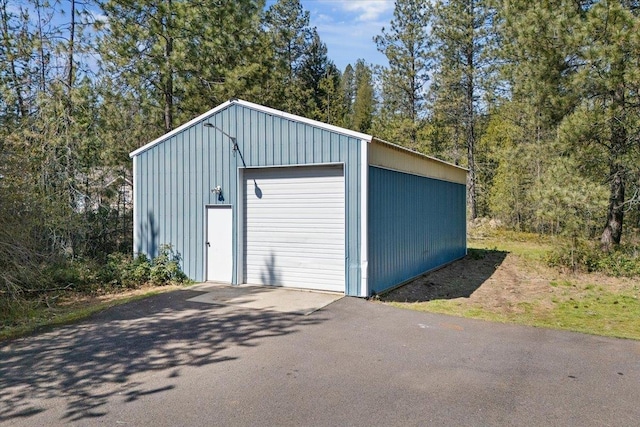 detached garage featuring a view of trees and driveway