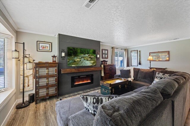living room featuring crown molding, visible vents, a large fireplace, and wood finished floors