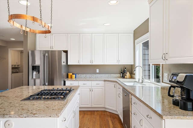 kitchen featuring white cabinets, a sink, light wood-style flooring, stainless steel appliances, and washer / dryer
