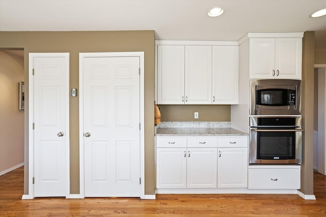 kitchen featuring light wood-style floors, white cabinetry, light stone countertops, and stainless steel appliances