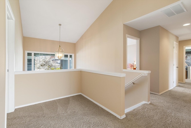 hallway featuring visible vents, an inviting chandelier, baseboards, carpet, and an upstairs landing