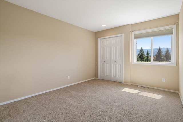 unfurnished bedroom with baseboards, carpet, visible vents, and a closet