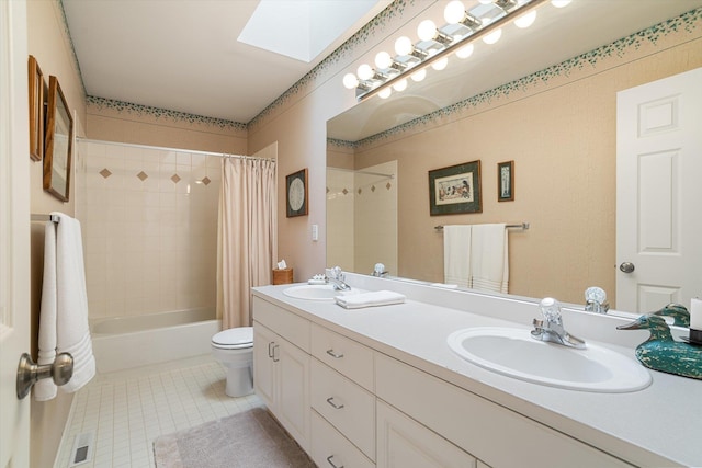 bathroom featuring a sink, tile patterned floors, a skylight, and toilet