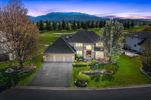 view of front facade with a garage, a mountain view, a yard, and concrete driveway