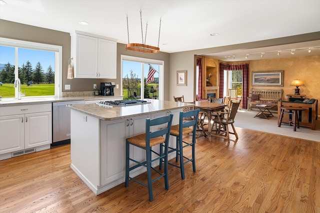 kitchen with stainless steel appliances, white cabinetry, a sink, and light wood-type flooring