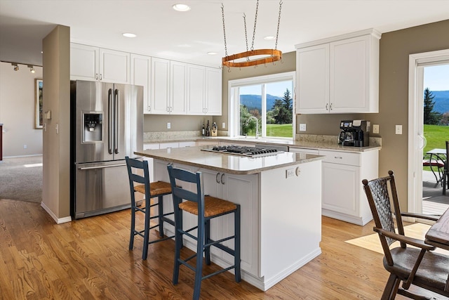 kitchen featuring appliances with stainless steel finishes, white cabinets, a center island, and a wealth of natural light