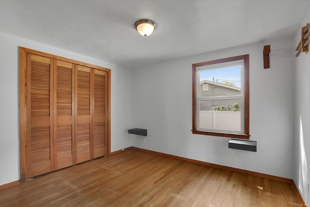 unfurnished bedroom featuring baseboards, light wood-style flooring, and a closet