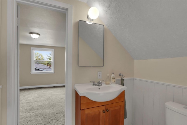 bathroom featuring toilet, a textured ceiling, lofted ceiling, and vanity