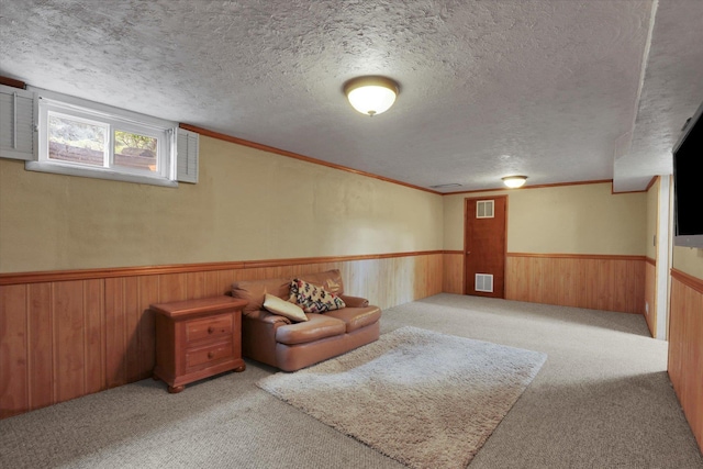 living area with visible vents, carpet, and a wainscoted wall