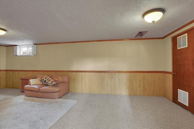 unfurnished room with carpet, wood walls, a textured ceiling, and visible vents
