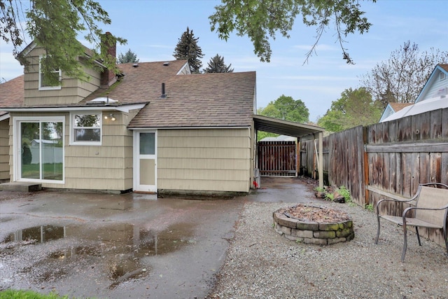 rear view of property featuring roof with shingles, fence, a fire pit, and a chimney
