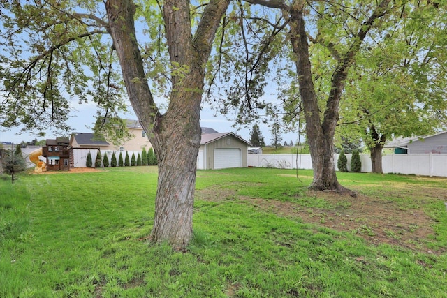 view of yard featuring a detached garage, fence, and a playground