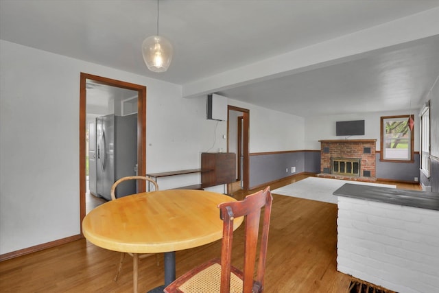 dining room with baseboards, a brick fireplace, and wood finished floors