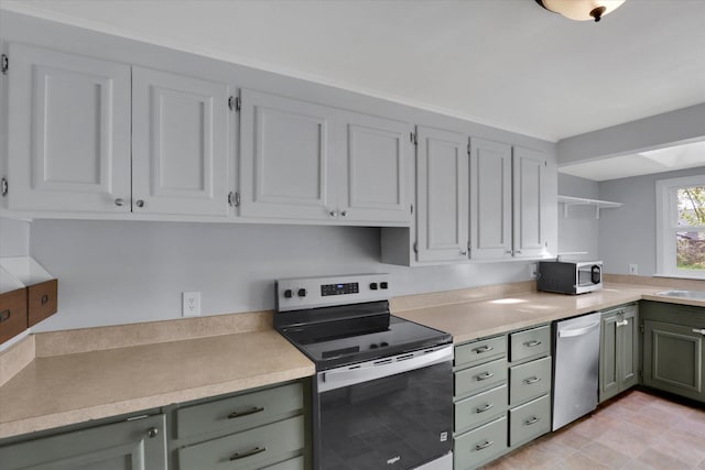 kitchen featuring open shelves, green cabinetry, appliances with stainless steel finishes, and light countertops