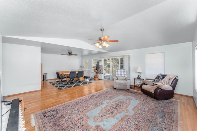 living area featuring baseboards, a ceiling fan, wood finished floors, and lofted ceiling