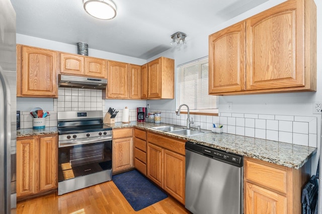 kitchen featuring a sink, tasteful backsplash, stainless steel appliances, and under cabinet range hood