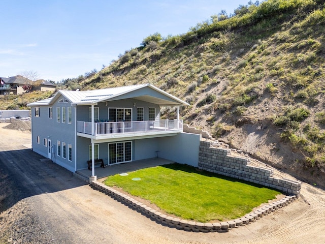 rear view of property featuring a lawn, a patio area, and a balcony