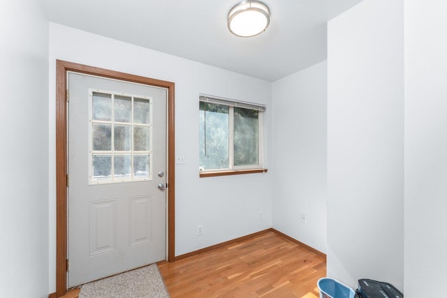 doorway featuring baseboards and light wood finished floors