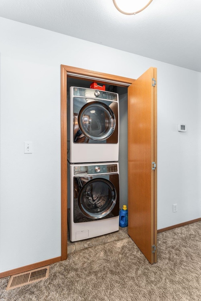 clothes washing area with laundry area, visible vents, baseboards, carpet, and stacked washer / drying machine
