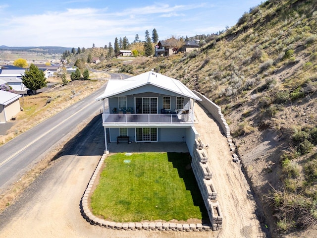 exterior space featuring a lawn, a balcony, and driveway