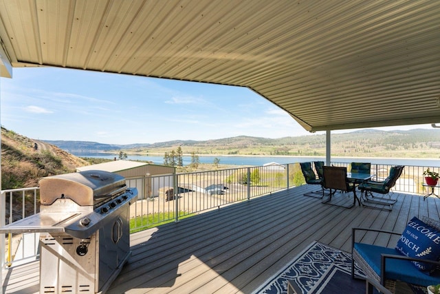 deck featuring a water and mountain view, outdoor dining space, and a grill