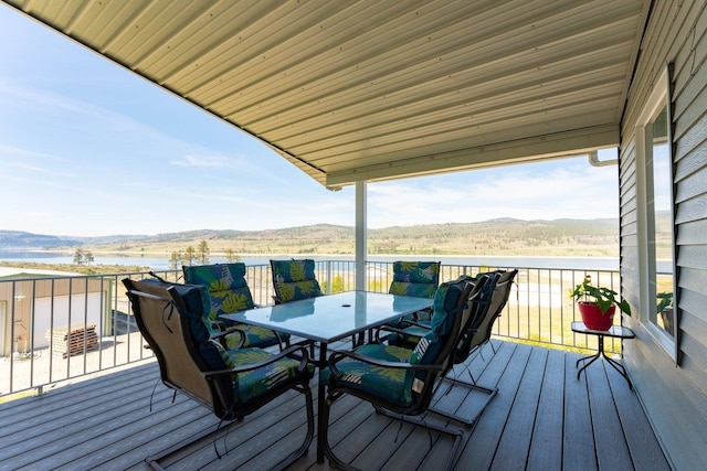 wooden deck with outdoor dining space and a water and mountain view