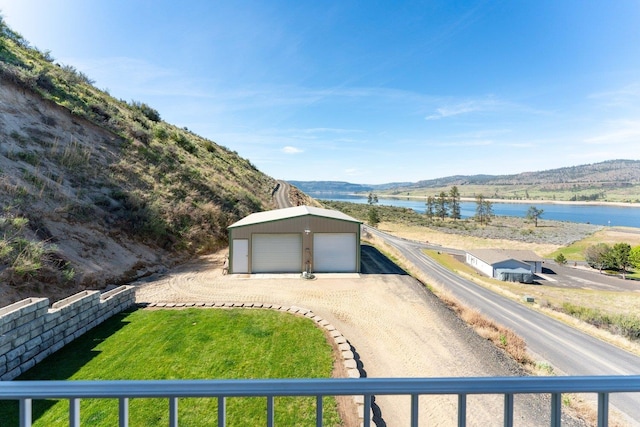 exterior space featuring a garage, an outbuilding, a water view, and driveway