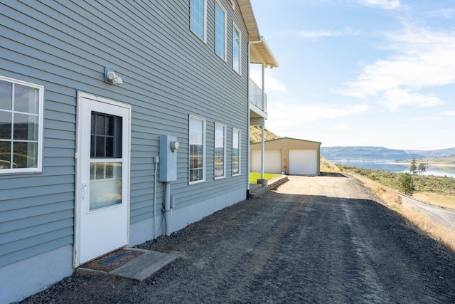 view of home's exterior featuring a detached garage, an outdoor structure, and a water view