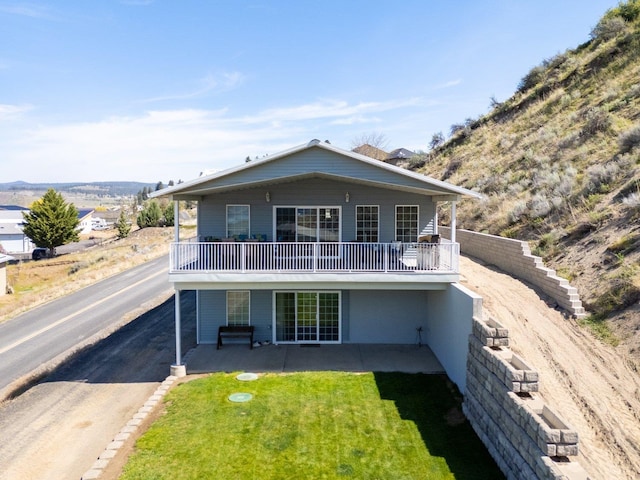 rear view of property featuring a yard and a balcony