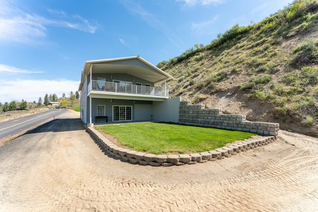 rear view of property featuring a yard and a balcony